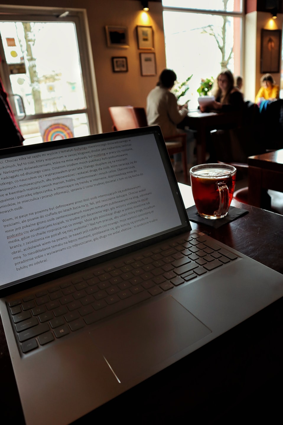 Silver laptop displaying Polish text on a wooden table.